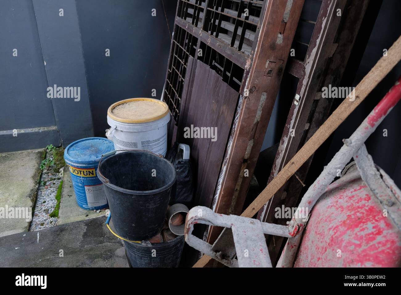 Stapel von Farbeimern und unbenutzten Gegenständen neben dem Haus Stockfoto