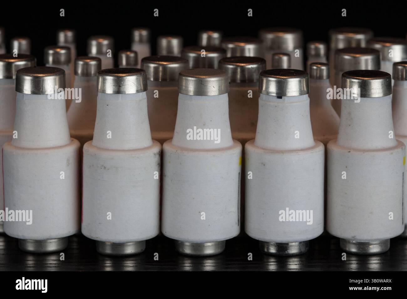 Nebeneinander angeordnete Sicherungen einschrauben. Porzellan, Staub und ruhige Symmetrie, ein dekoratives Ensemble technischer Relikte. Stockfoto Nebeneinander angeordnete Sicherungen einschrauben. Porzellan, Staub und ruhige Symmetrie, ein dekoratives Ensemble technischer Relikte. Stockfoto