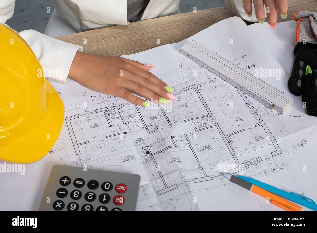 Sorgfältige Analyse von Bauplänen auf einer Baustelle für eine bessere Planung und einen Gesamterfolg Stockfoto