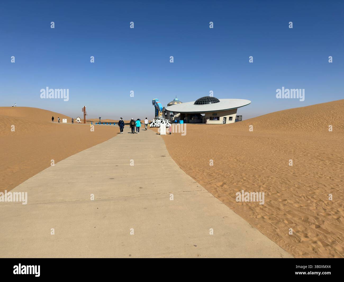 Ein futuristisches Restaurant in Form eines Raumschiffs befindet sich inmitten einer riesigen Wüstenlandschaft. - Smartphone-aufgenommenes Stockfoto