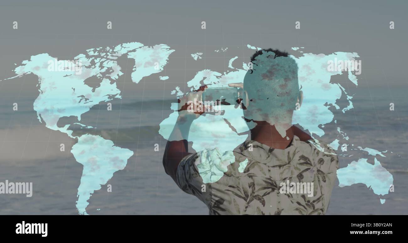 Weltkarte über Rückansicht eines afroamerikanischen Mannes, der Fotos von seinem Smartphone am Strand macht Stockfoto