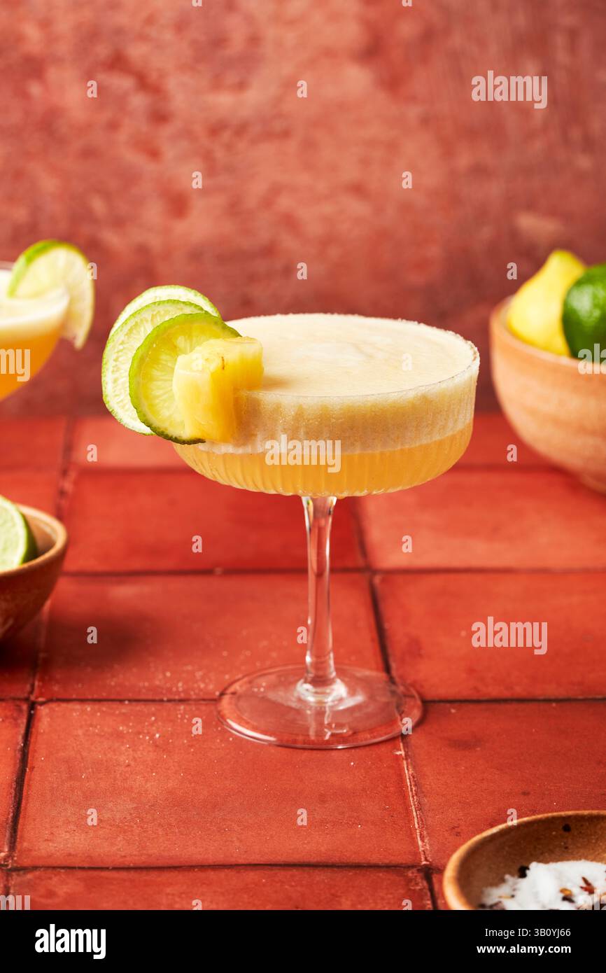 Ananas-Lime-Margarita auf Terrakottafliesen-Oberfläche mit Chili-gesalzenem Rand Stockfoto