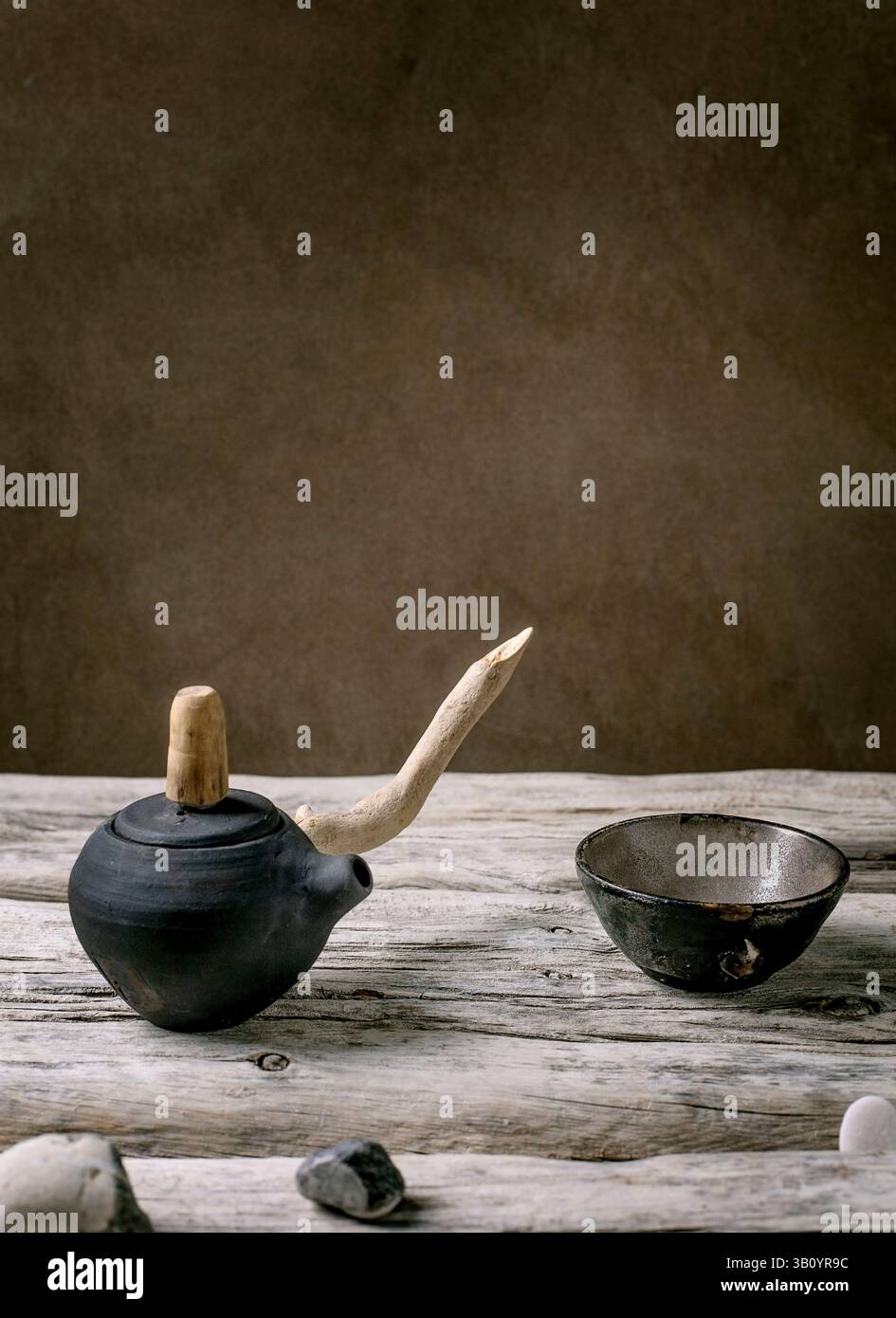 Originale handgefertigte Keramik-Teekanne mit Holzgriff und Tassen für traditionellen chinesischen Tee auf einem alten Holztisch. Dekorative Meereskiesel alle A Stockfoto