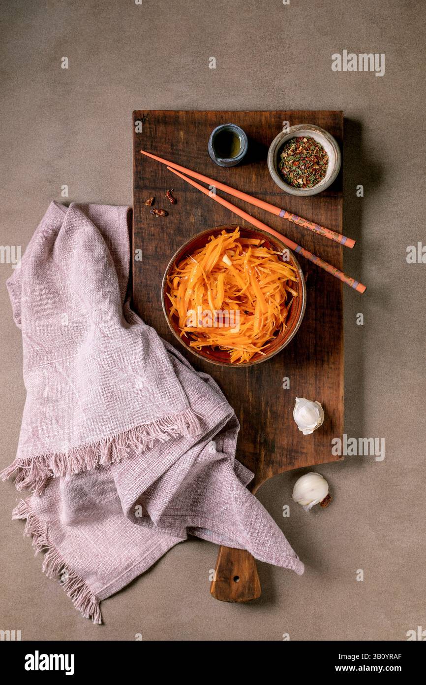 Gericht der koreanischen und asiatischen Küche: Gemüsesalat marinierte Karotten mit Knoblauch. Serviert in einer Keramikschale mit Stäbchen. Würze in kleinen Schüsseln auf M Stockfoto