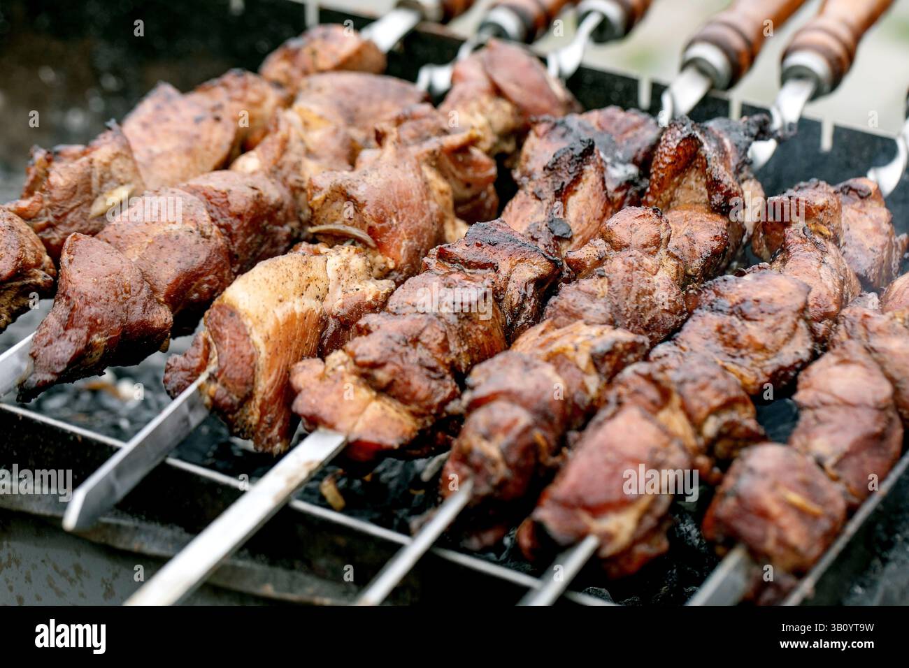 Saftige gegrillte Fleischspieße, die auf dem Grill kochen. Marinierte Fleischstücke, die auf Metallspießen über heißen Kohlen geröstet werden. Traditionelles Grillmetho Stockfoto