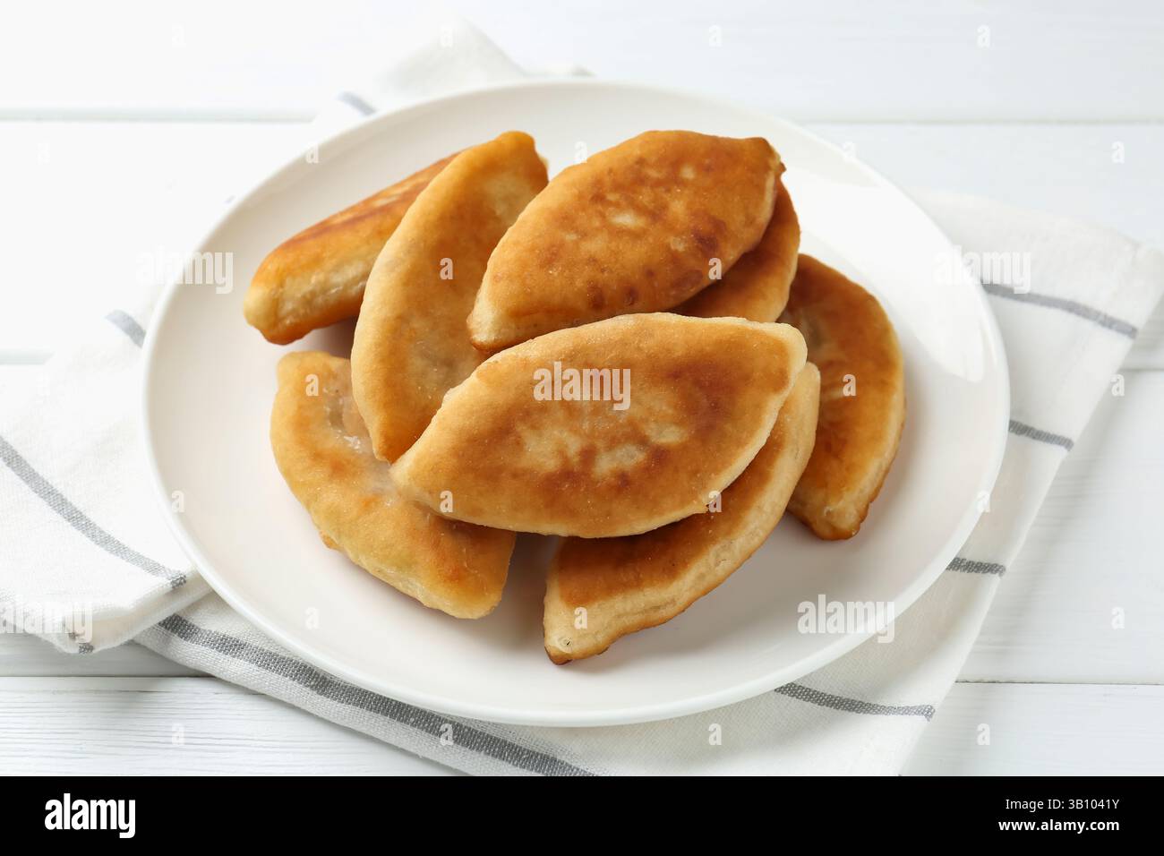 Köstliche gebratene Pyrizhky (gefüllte Kuchen) auf weißem Holztisch, Nahaufnahme Stockfoto Köstliche gebratene Pyrizhky (gefüllte Kuchen) auf weißem Holztisch, Nahaufnahme Stockfoto