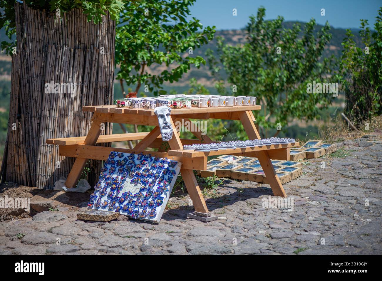Eine Sammlung traditioneller Souvenirs aus dem Dorf, die elegant auf einem Holztisch angeordnet sind und handgefertigtes Kunsthandwerk, rustikale Dekoration und lokale Schätze zeigen Stockfoto