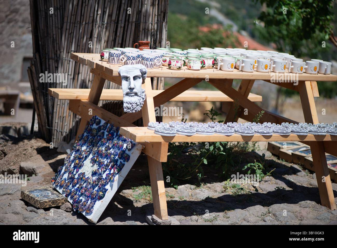 Eine Sammlung traditioneller Souvenirs aus dem Dorf, die elegant auf einem Holztisch angeordnet sind und handgefertigtes Kunsthandwerk, rustikale Dekoration und lokale Schätze zeigen Stockfoto