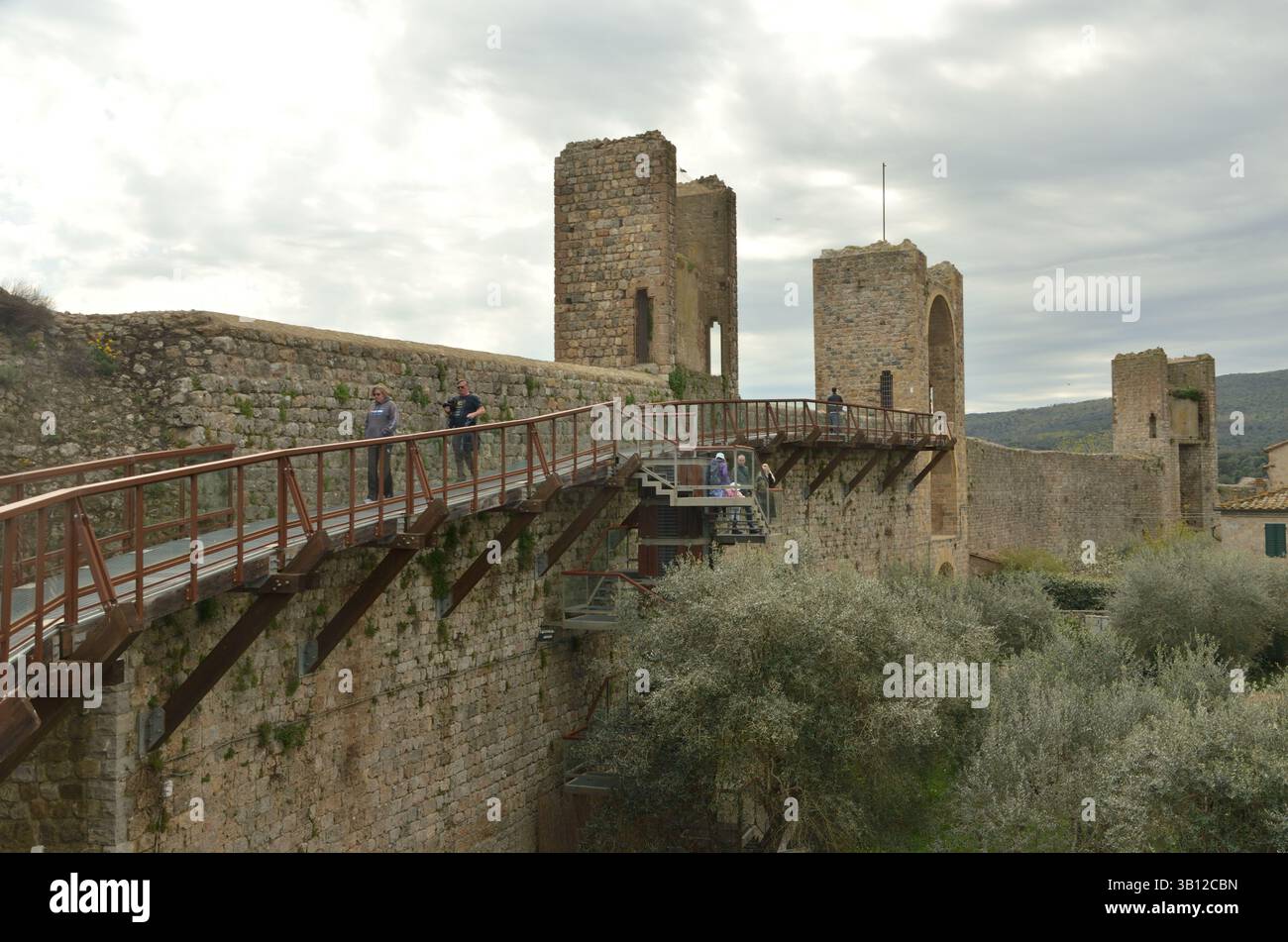 Ein moderner freitragender Fußweg an den historischen Mauern des befestigten Dorfes Monteriggioni in der Toskana, Italien. Stockfoto