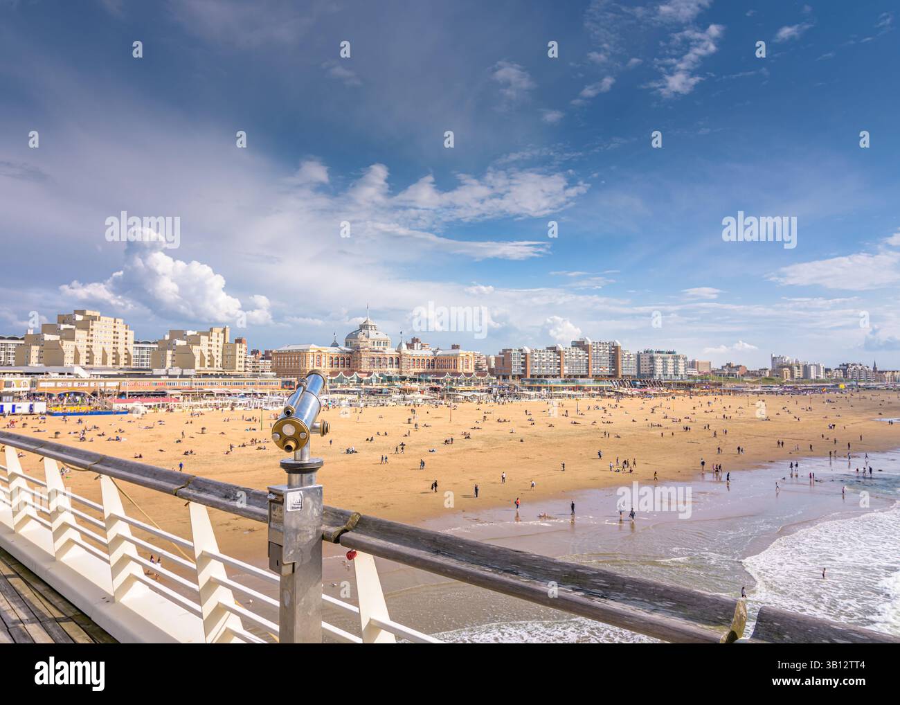 Die Menschen genießen sich am Nordseestrand in Scheveningen mit dem Boulevard im Hintergrund Stockfoto