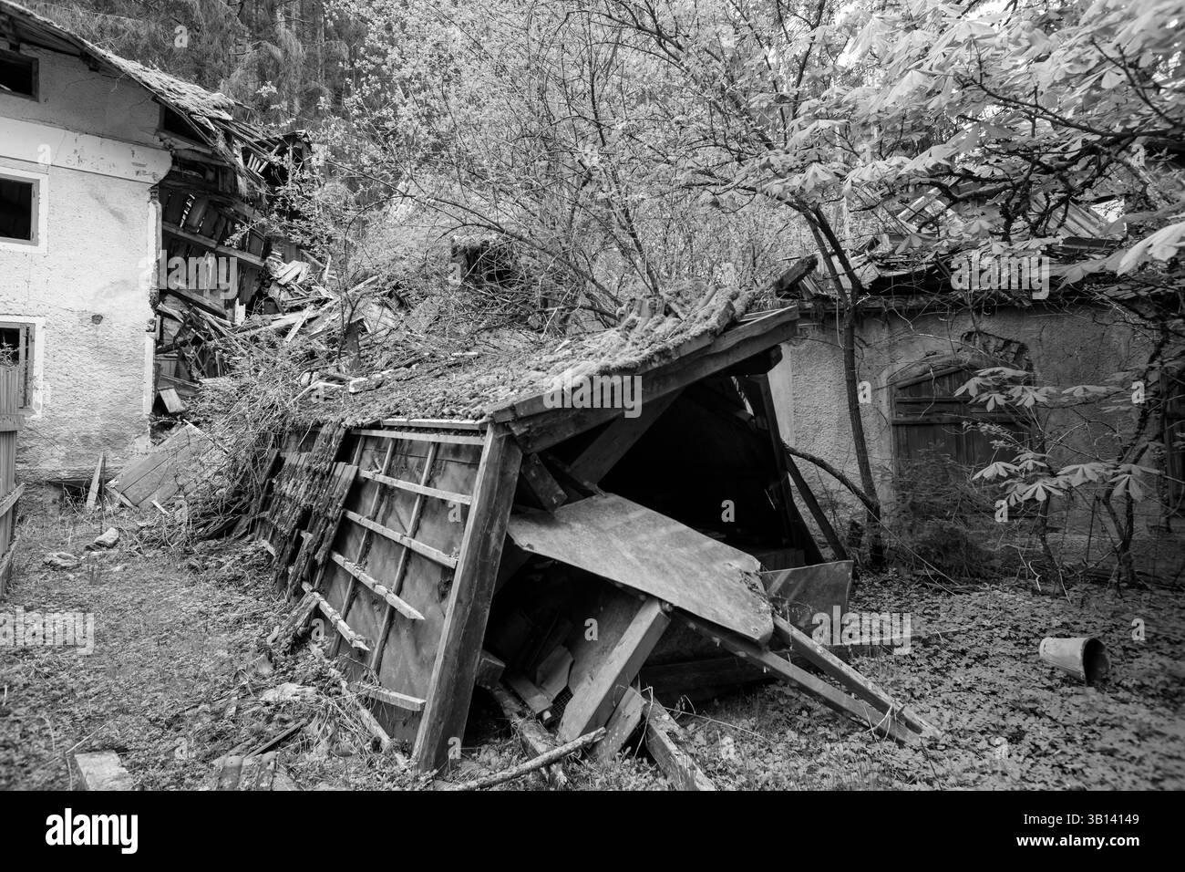 Bad Illstern, italien, verlor seinen Platz. Schwarz-weiß-Bild von baufälligen Gebäuden, darunter ein eingestürzter Schuppen und ein teilweise zerstörtes Haus, umgeben Stockfoto