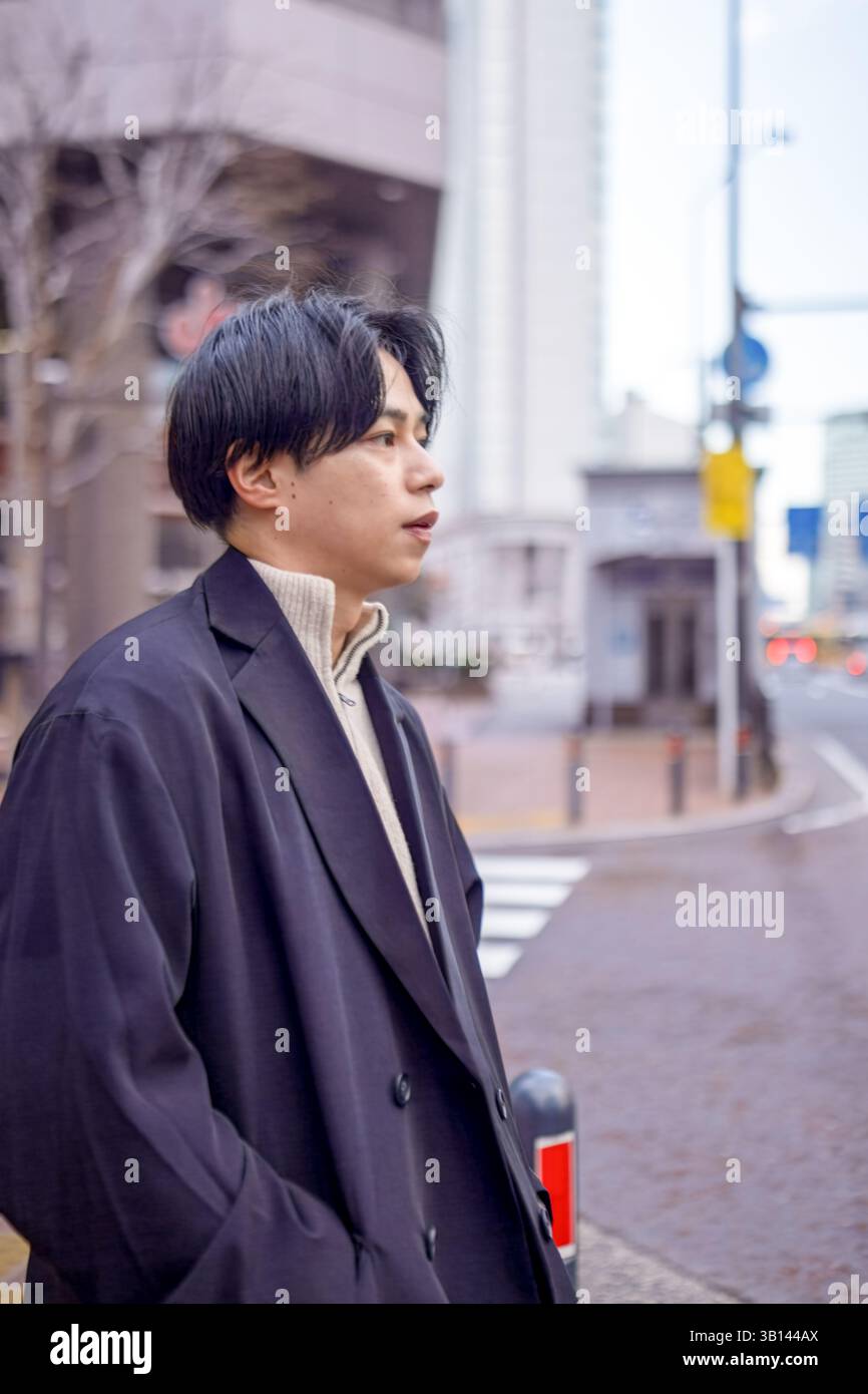 Ein Japaner mit 20 Jahren steht an einer Fußgängerüberfahrt in Minato Mirai, Yokohama, Präfektur Kanagawa, und wartet auf die Ampel in der Höhe Stockfoto