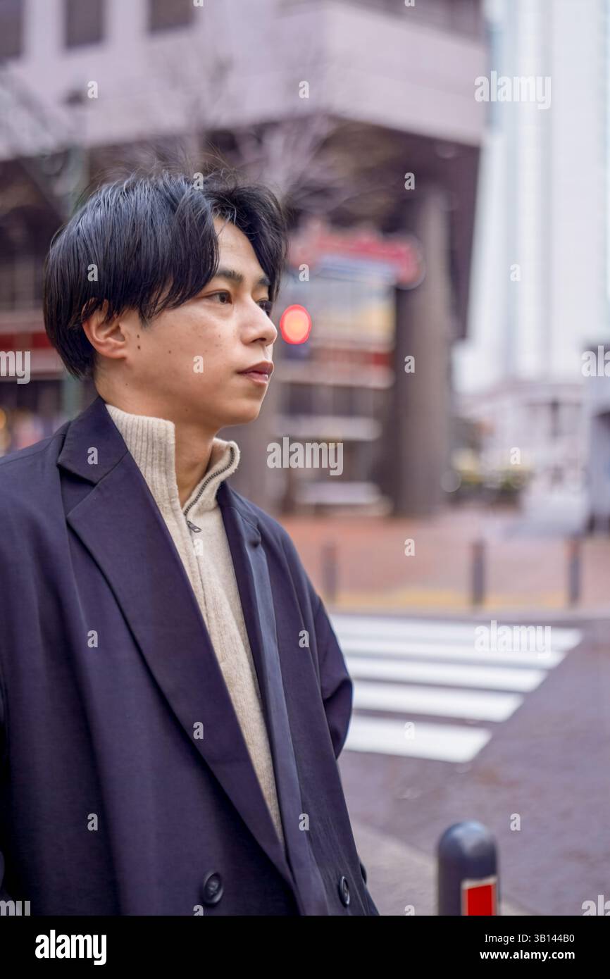 Ein Japaner mit 20 Jahren steht an einer Fußgängerüberfahrt in Minato Mirai, Yokohama, Präfektur Kanagawa, und wartet auf die Ampel in der Höhe Stockfoto