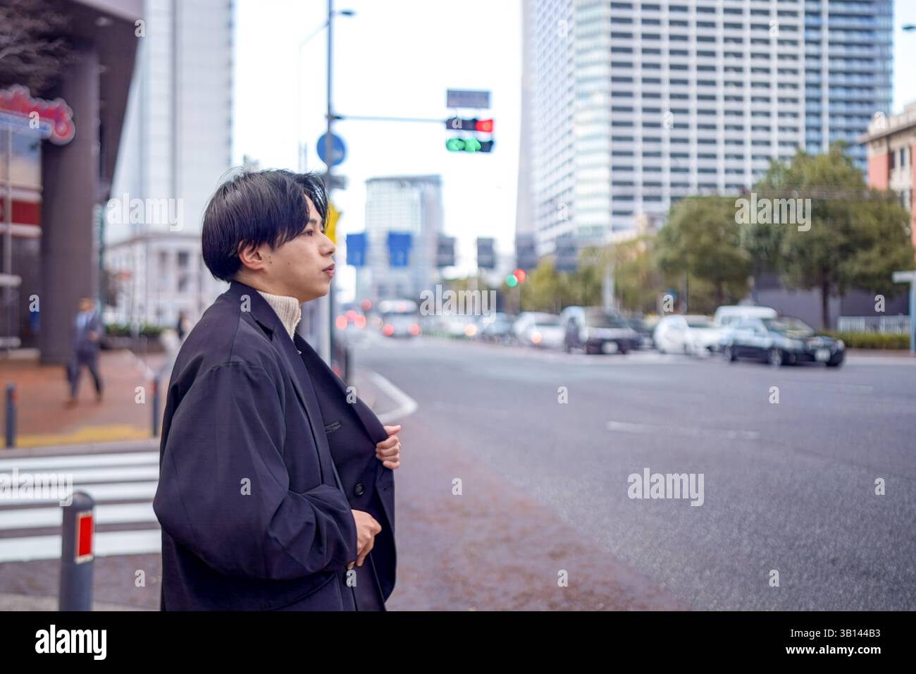 Ein Japaner mit 20 Jahren steht an einer Fußgängerüberfahrt in Minato Mirai, Yokohama, Präfektur Kanagawa, und wartet auf die Ampel in der Höhe Stockfoto