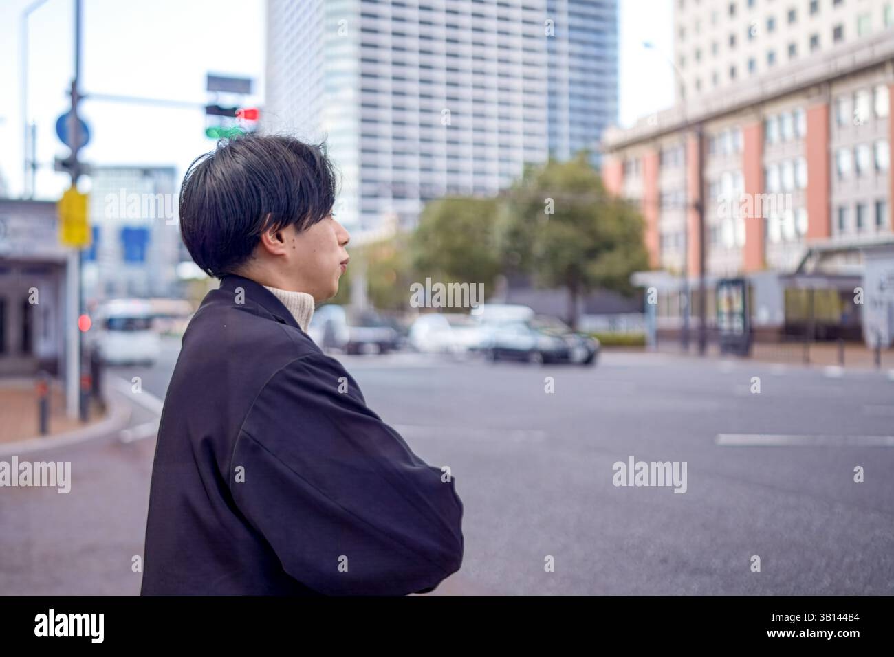 Ein Japaner mit 20 Jahren steht an einer Fußgängerüberfahrt in Minato Mirai, Yokohama, Präfektur Kanagawa, und wartet auf die Ampel in der Höhe Stockfoto