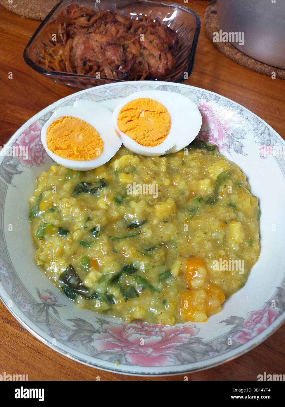 Bubur manado oder Tinutuan Brei, traditioneller Brei. Manadonesischer Reisbrei, gemischt mit Kürbis, Mais, Gemüse. Serviert mit gesalzenem Tofu-Fisch. Stockfoto