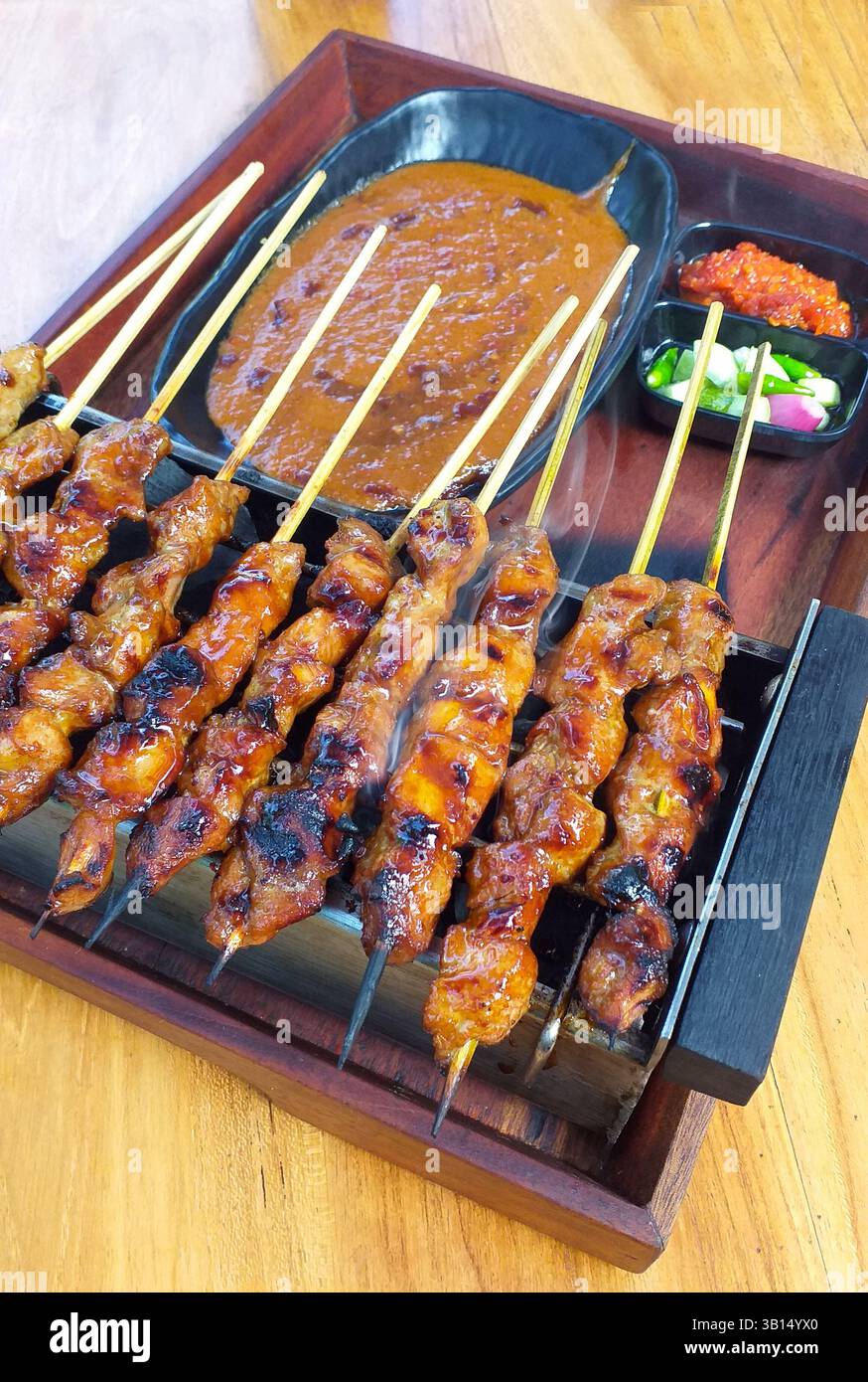Indonesischer Sate Ayam wird mit Erdnusssauce, eingelegtem Gemüse und Chili-Sauce gegrillt. Stockfoto