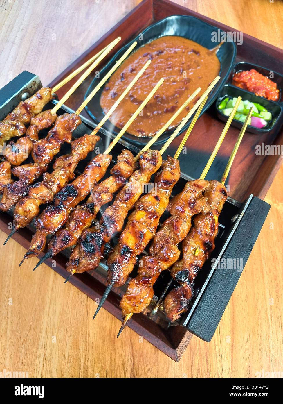 Indonesischer Sate Ayam wird mit Erdnusssauce, eingelegtem Gemüse und Chili-Sauce gegrillt. Stockfoto
