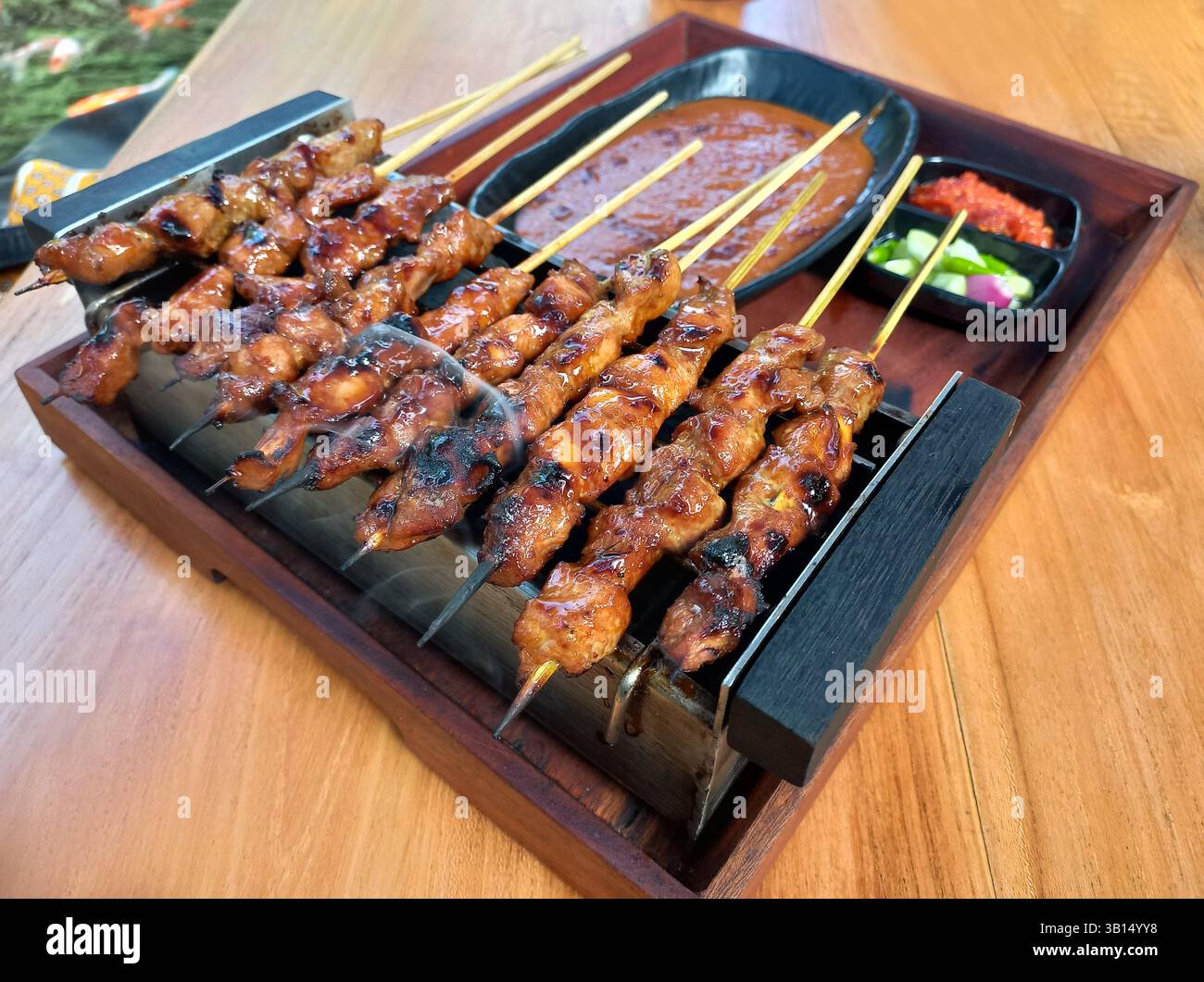 Indonesischer Sate Ayam wird mit Erdnusssauce, eingelegtem Gemüse und Chili-Sauce gegrillt. Stockfoto
