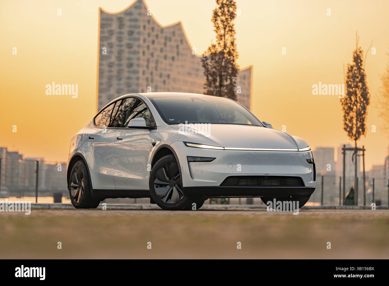 Futuristisches weißes Elektroauto vor einem modernen Gebäude in der Stadt bei Sonnenuntergang, Tesla New Model Y, Deutschland, Europa Stockfoto