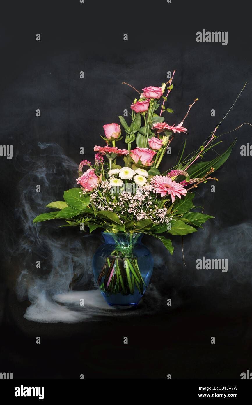 Ein bunter Blumenstrauß in einer Vase auf schwarzem Hintergrund mit Nebeleffekt Stockfoto