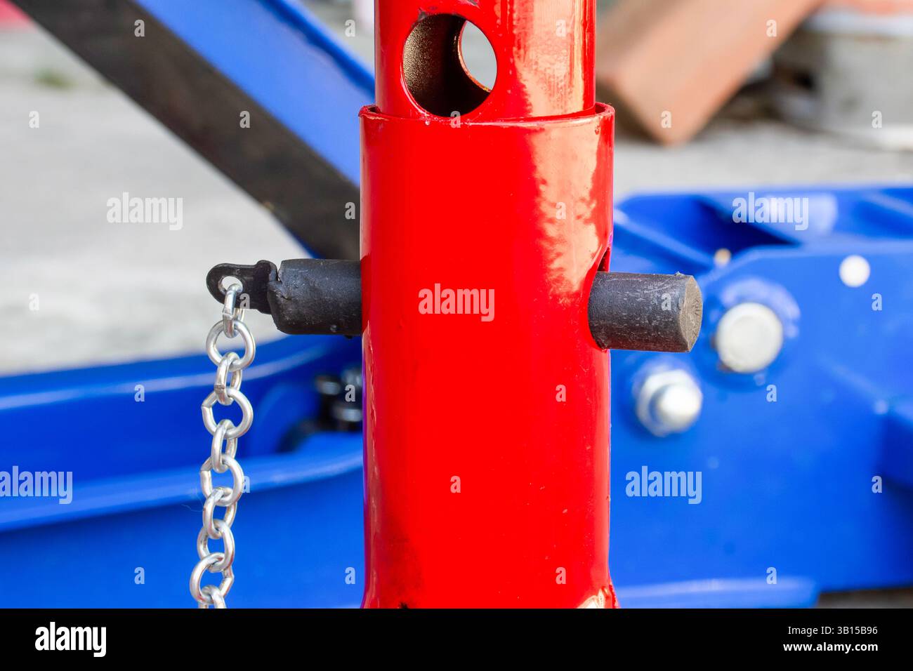 Nahaufnahme des höhenverstellbaren Verriegelungsstifts und der Stützsäule eines roten Unterstellbodens, der für die Fahrzeugwartung und das sichere Anheben von Fahrzeugen verwendet wird. Auto Stockfoto