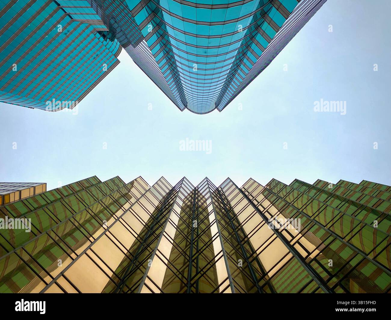 Eine vertikale Perspektive mit Blick zum Himmel, eingerahmt von dem Spiegelglas des Royal Pacific Hotel und des Gateway, Kowloon, Hongkong, China. Stockfoto