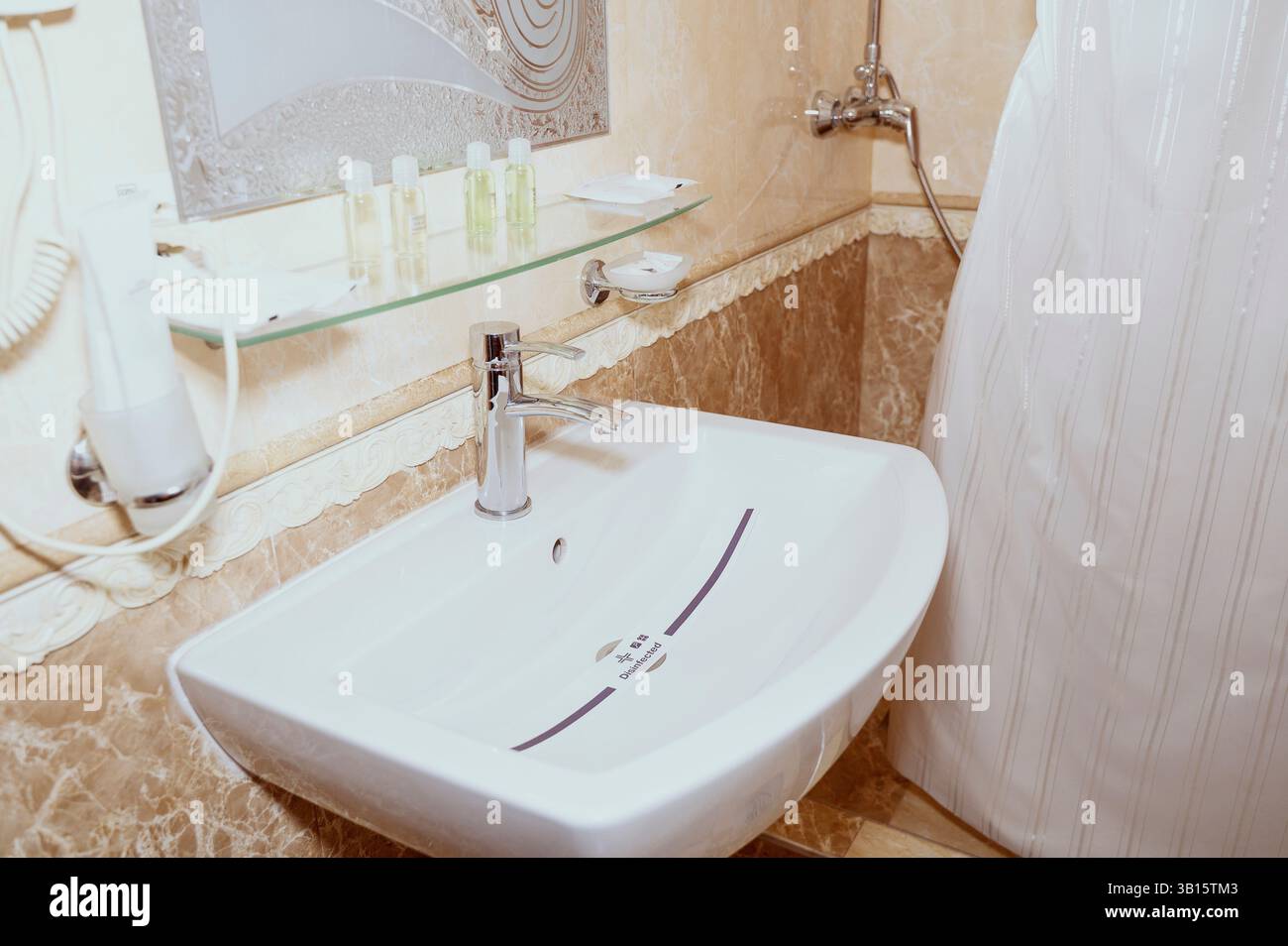 Hotelbadezimmer mit Spiegel und desinfiziertem Waschbecken. Waschzubehör im Hotelbad Stockfoto