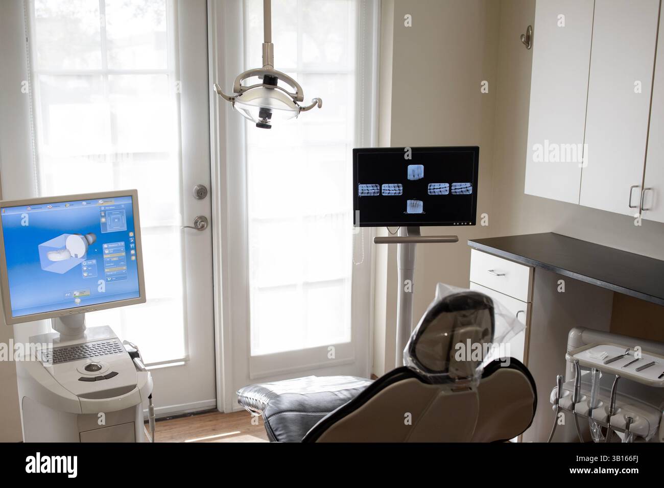 Zahnarztstuhl mit Monitoren nach hellen Türen Stockfoto