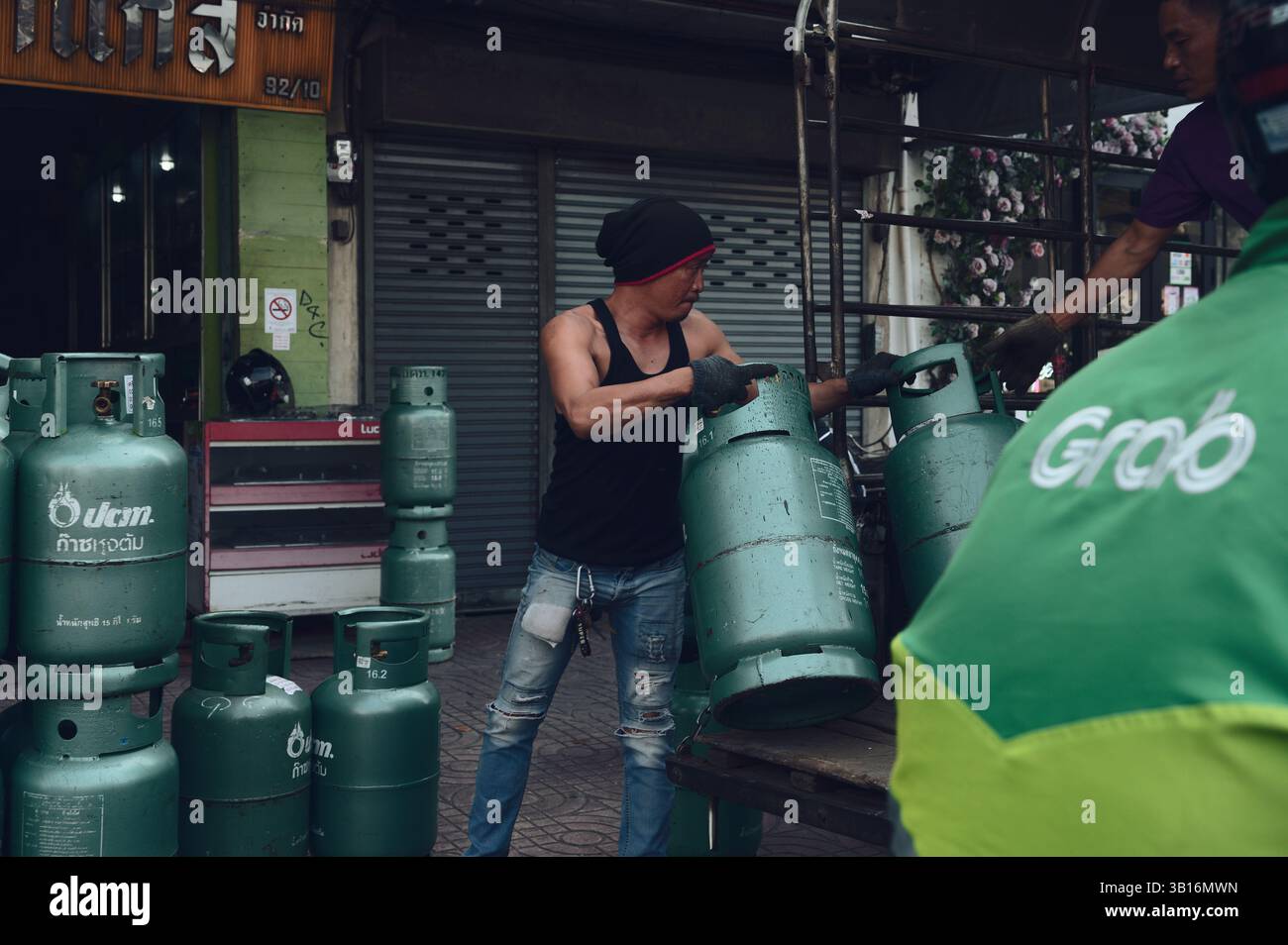 Ein harter Mann aus Bangkok lädt Gasflaschen mit geübter Leichtigkeit auf einen Lkw Stockfoto