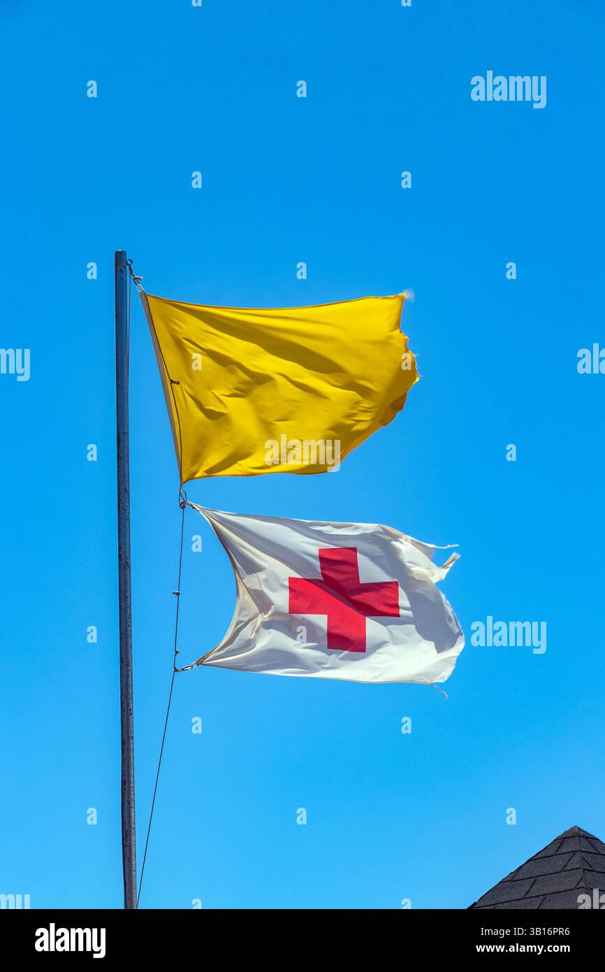 Rotes Kreuz und gelbe Flagge vor blauem Himmel am Strand teneriffas, Warnung vor gefährlichen Badegebieten des Meeres und Rettungsschwimmer im Dienst Stockfoto
