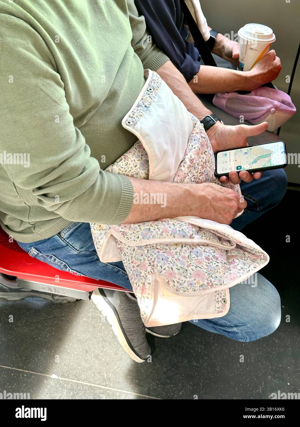 Ein paar Touristen in einer Straßenbahn in Wien mit einem Smartphone mit Google Maps und einem Kaffee - Smartphone-aufgenommenes Stockfoto