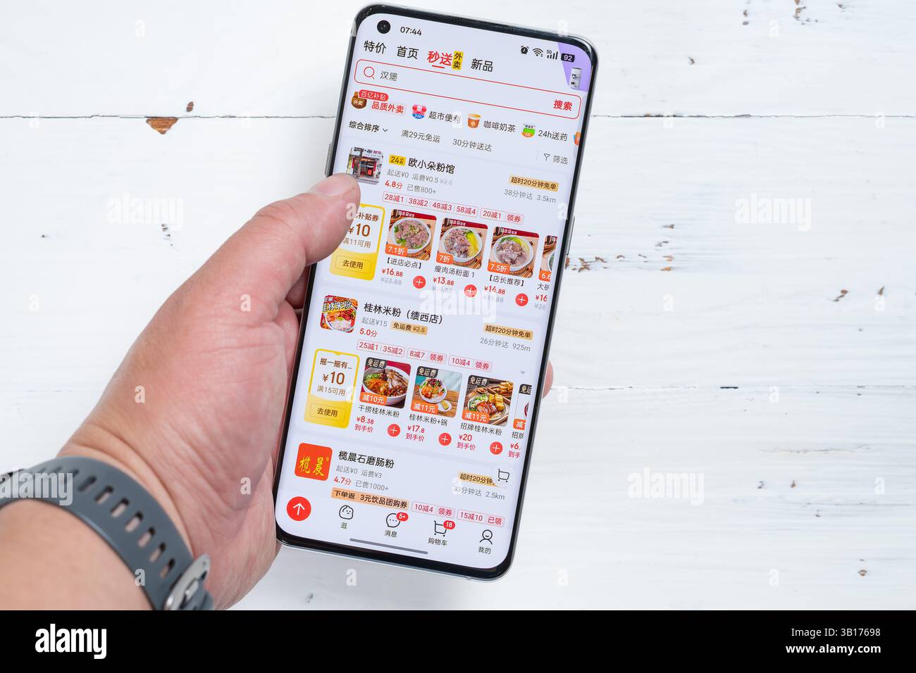 Zhongshan, China-25. April 2025: Mann mit einem Handy und auf der Suche nach Nahrungslieferungen auf JD in horizontaler Zusammensetzung. Stockfoto