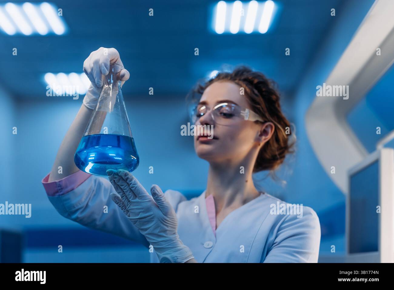 Medizinwissenschaftlerin in Brillen, die chemische Flüssigkeit in Reagenzglasanalyse halten. Fortschrittliches wissenschaftliches Labor für Pharmazeutische Medizin Stockfoto