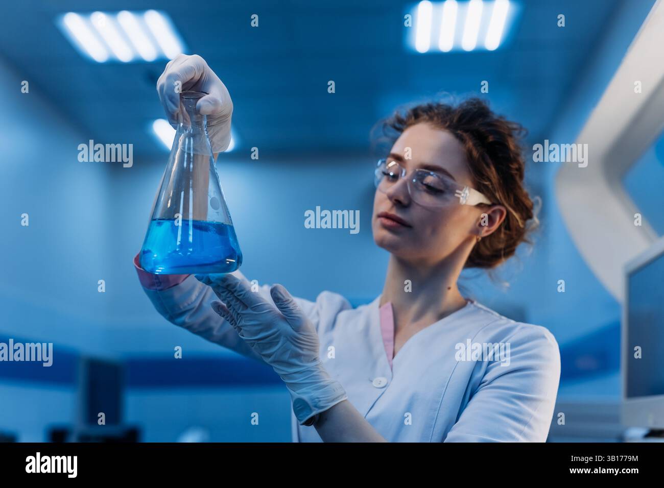 Medizinwissenschaftlerin in Brillen, die chemische Flüssigkeit in Reagenzglasanalyse halten. Fortschrittliches wissenschaftliches Labor für Pharmazeutische Medizin Stockfoto