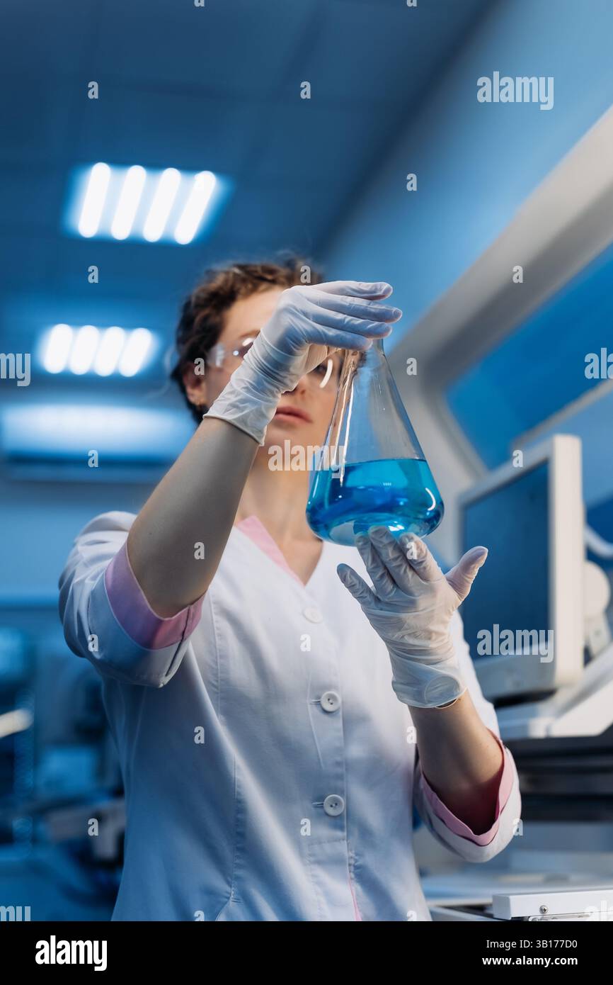 Medizinwissenschaftlerin in Brillen, die chemische Flüssigkeit in Reagenzglasanalyse halten. Fortschrittliches wissenschaftliches Labor für Pharmazeutische Medizin Stockfoto