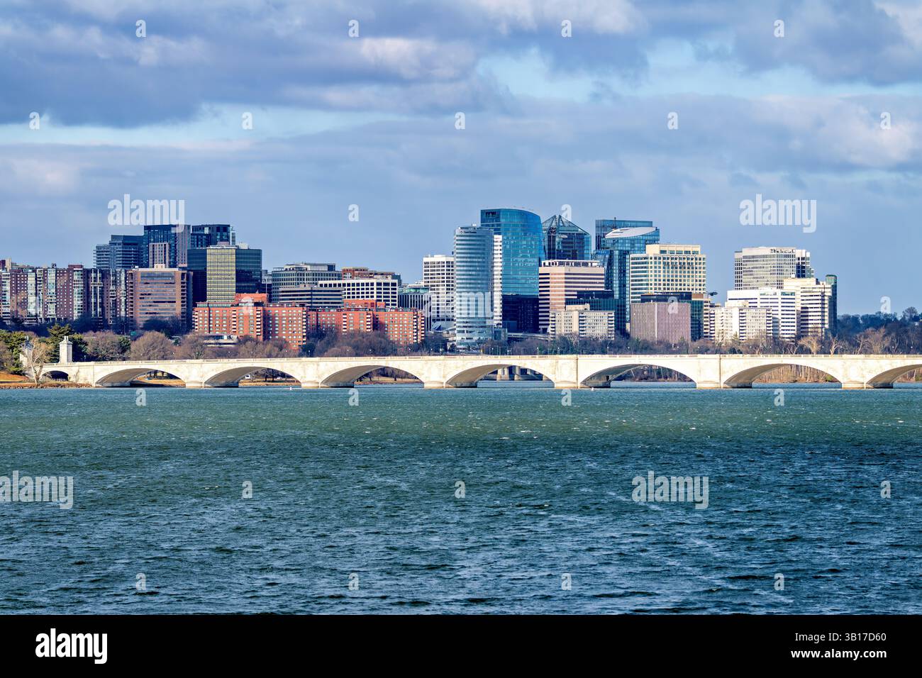 ARLINGTON, Virginia – die Skyline von Rosslyn erhebt sich hinter der Arlington Memorial Bridge an einem windigen Wintertag entlang des Potomac River. Die 1932 fertiggestellte neoklassizistische Brücke verbindet den Arlington National Cemetery mit dem Lincoln Memorial in Washington DC. Die 2.163 Meter lange Arlington Memorial Bridge dient sowohl als symbolische als auch physische Verbindung zwischen Nord und Süd und erinnert an die Wiedervereinigung des Landes nach dem Bürgerkrieg. Stockfoto