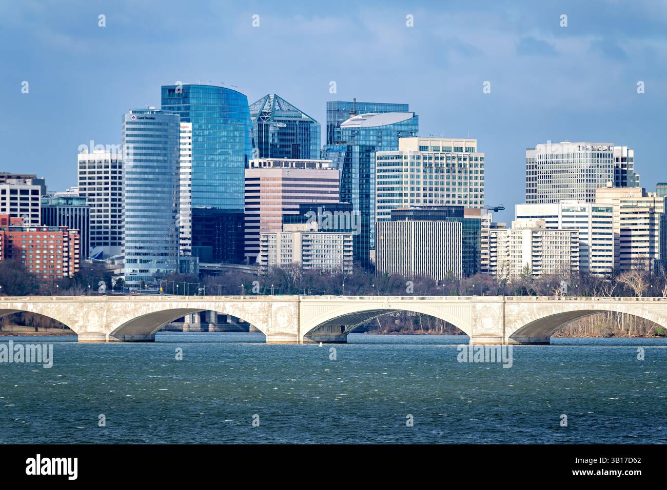 ARLINGTON, Virginia – die Skyline von Rosslyn erhebt sich hinter der Arlington Memorial Bridge an einem windigen Wintertag entlang des Potomac River. Die 1932 fertiggestellte neoklassizistische Brücke verbindet den Arlington National Cemetery mit dem Lincoln Memorial in Washington DC. Die 2.163 Meter lange Arlington Memorial Bridge dient sowohl als symbolische als auch physische Verbindung zwischen Nord und Süd und erinnert an die Wiedervereinigung des Landes nach dem Bürgerkrieg. Stockfoto