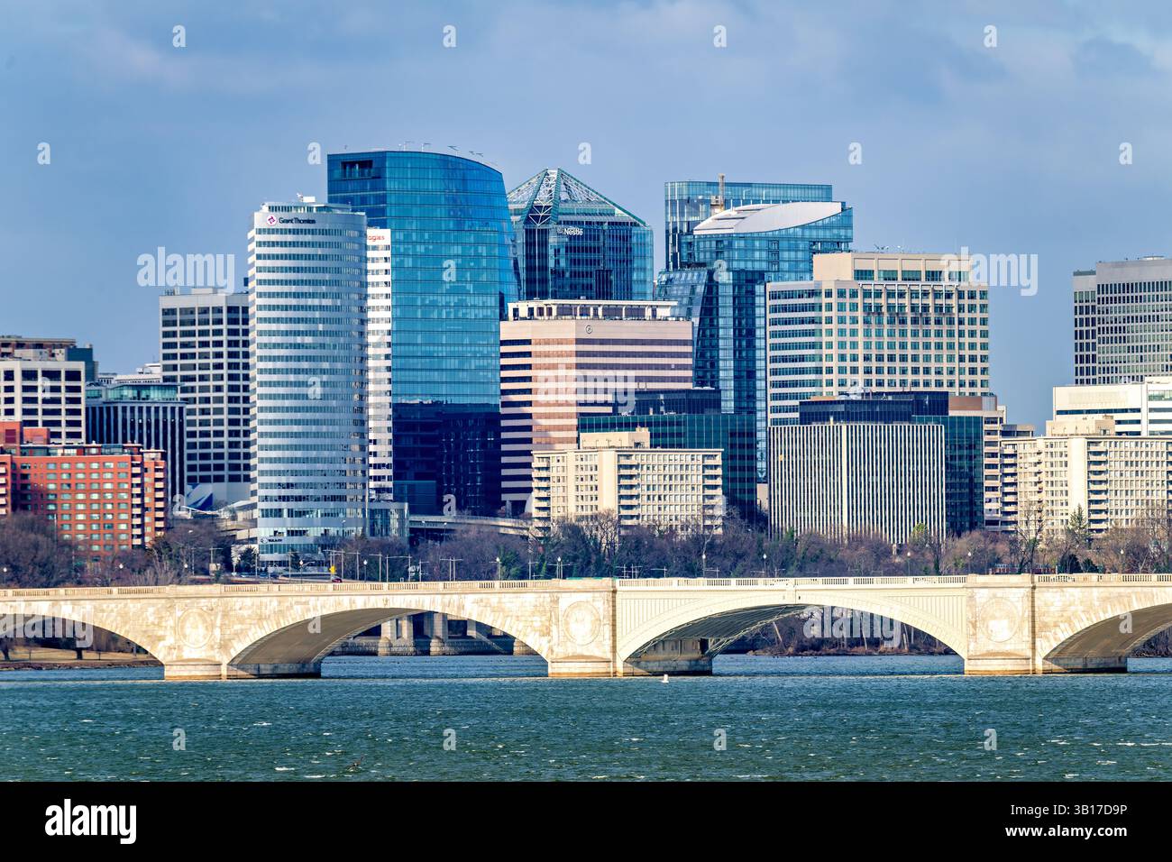 ARLINGTON, Virginia – die Skyline von Rosslyn erhebt sich hinter der Arlington Memorial Bridge an einem windigen Wintertag entlang des Potomac River. Die 1932 fertiggestellte neoklassizistische Brücke verbindet den Arlington National Cemetery mit dem Lincoln Memorial in Washington DC. Die 2.163 Meter lange Arlington Memorial Bridge dient sowohl als symbolische als auch physische Verbindung zwischen Nord und Süd und erinnert an die Wiedervereinigung des Landes nach dem Bürgerkrieg. Stockfoto