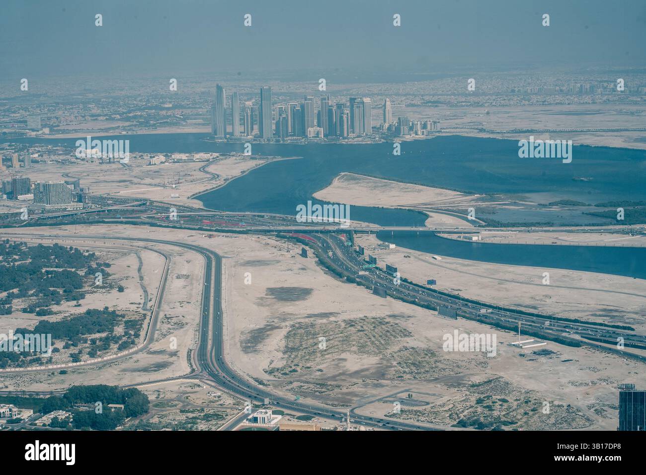 Aus der Vogelperspektive der Stadt Abu Dhabi, VAE, mit Blick auf die Stadt, Wasserstraßen, Straßen, und Wüstenlandschaft unter einem trüben Himmel. Stockfoto