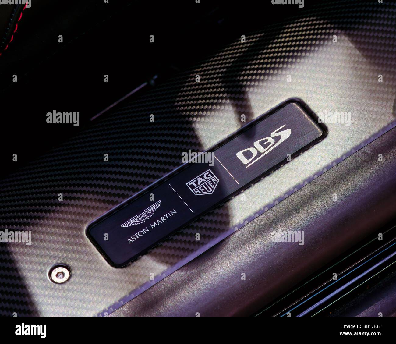Nahaufnahme des Motorraums aus Kohlefaser in einem Aston Martin DBS mit den Logos Tag Heuer und Aston Martin. Stockfoto