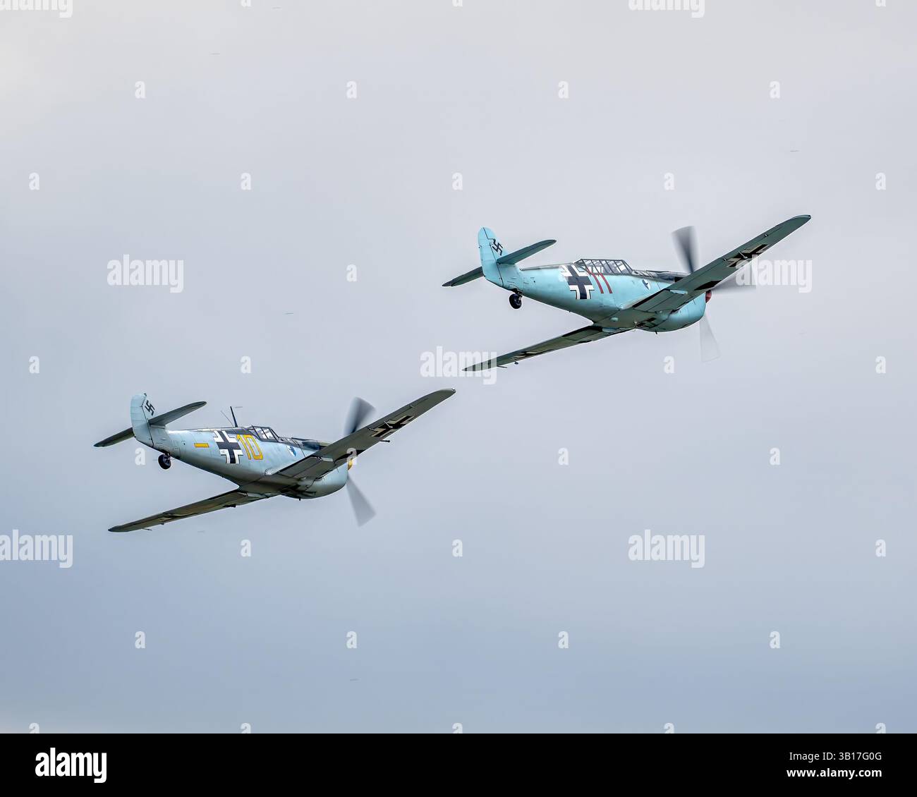 Zwei Messerschmitt Bf 109 Kampfflugzeuge in Formation gegen bewölkten Himmel während einer Flugshow in Duxford, England. Stockfoto