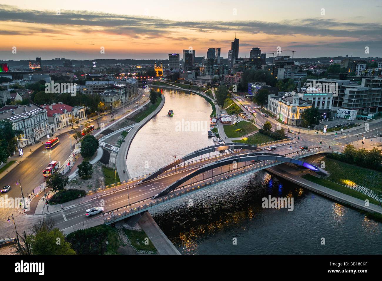 Die Mindaugas-Brücke überquert den Neris River und Vilnius Stadtlandschaft am Horizont am Abend Stockfoto