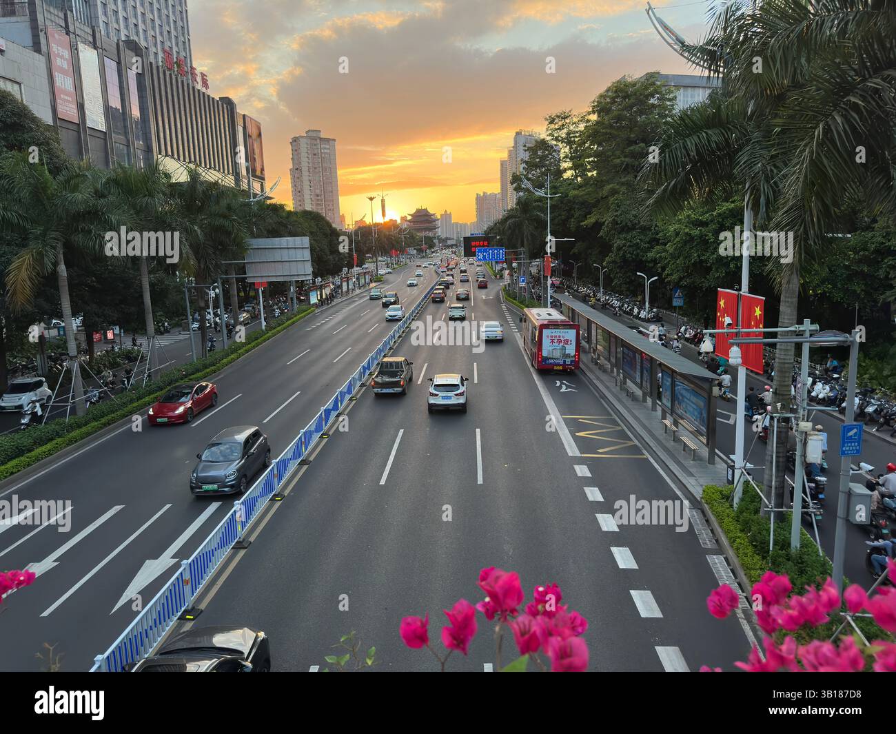 Nanning, China - 8. Oktober 2023. Der Sonnenuntergang über einer geschäftigen Stadtstraße in Nanning, China, mit Autos, Bussen und Gebäuden, schafft eine lebendige Szene. - Smartphone-aufgenommenes Stockfoto