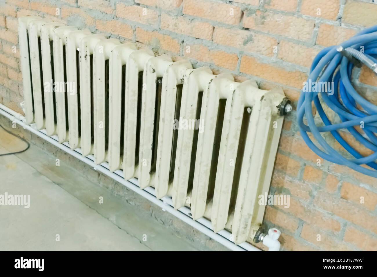 Der alte gusseiserne Heizkörper wird während des Bauens des Hauses anstelle des neuen Heizkörpers eingesetzt. Stockfoto