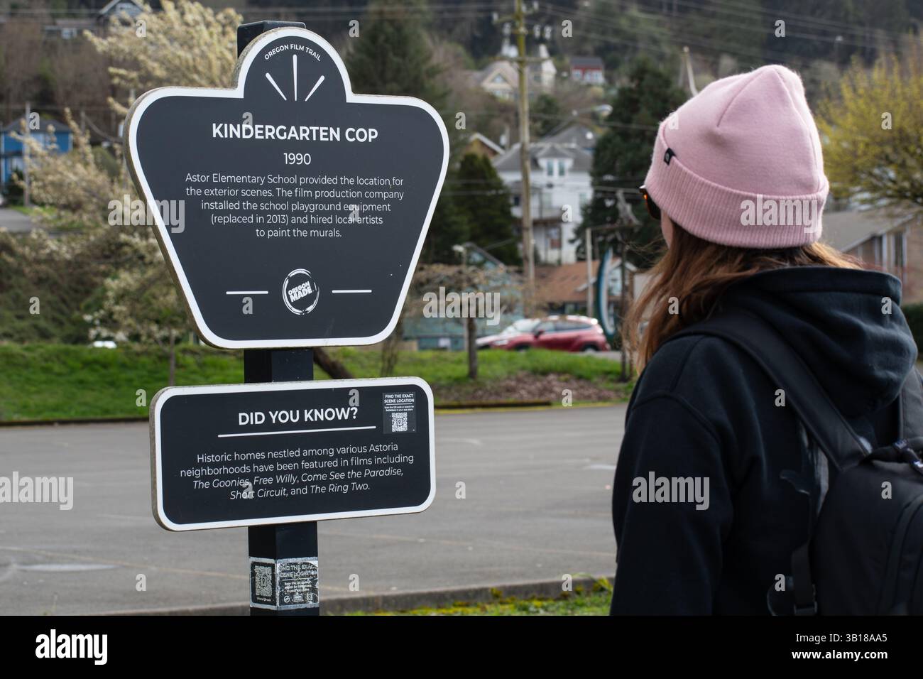 Astoria, Oregon, USA – 10. April 2025: Eine Frau liest das Drehortsschild des Kindergartens auf dem Oregon Film Trail. Stockfoto