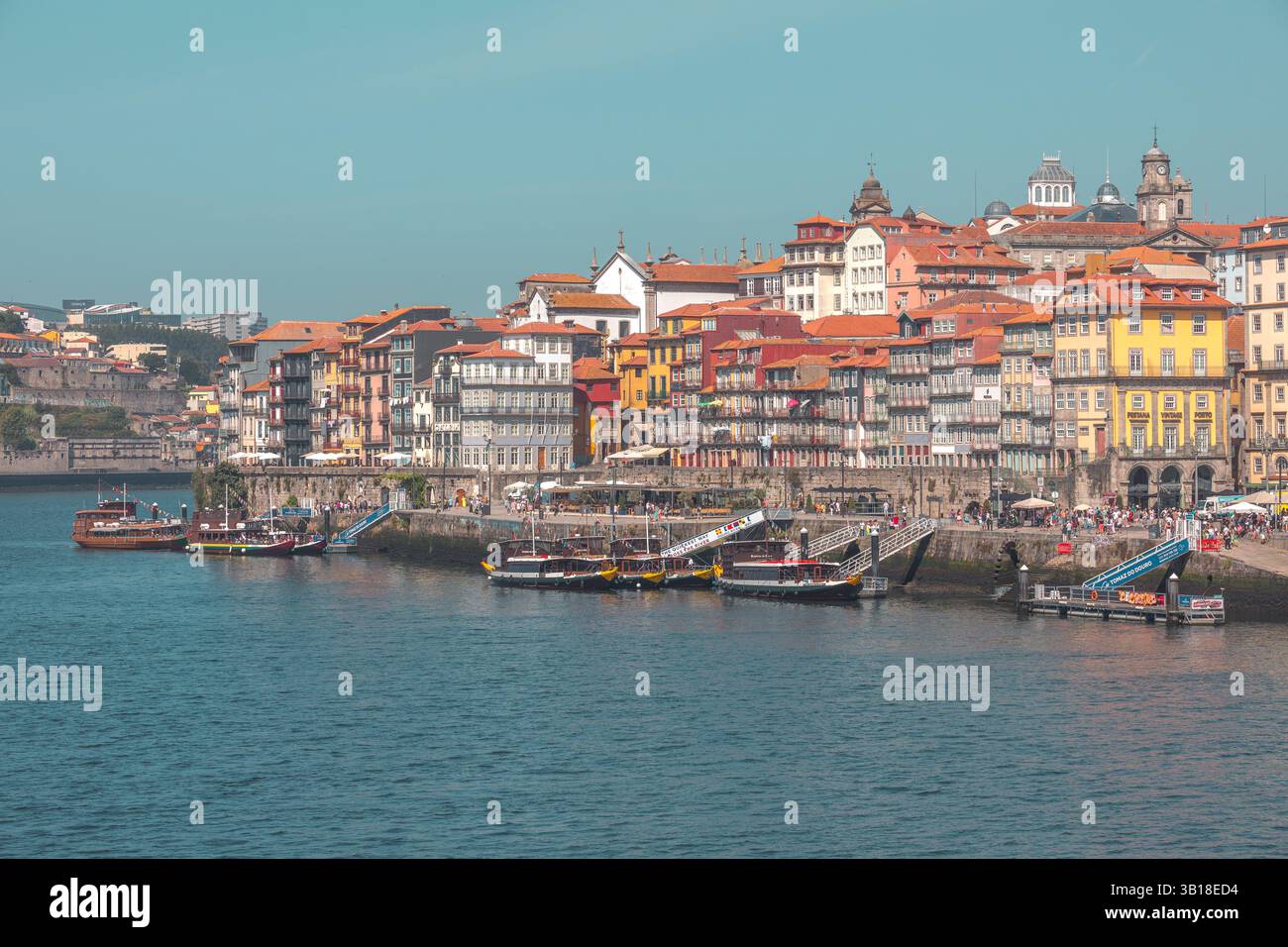 Farbenfrohe historische Gebäude und traditionelle Ragelo-Boote entlang des Flusses Douro in Porto, Portugal, die den lebhaften Charme der Stadt am Flussufer zum Ausdruck bringen. Stockfoto