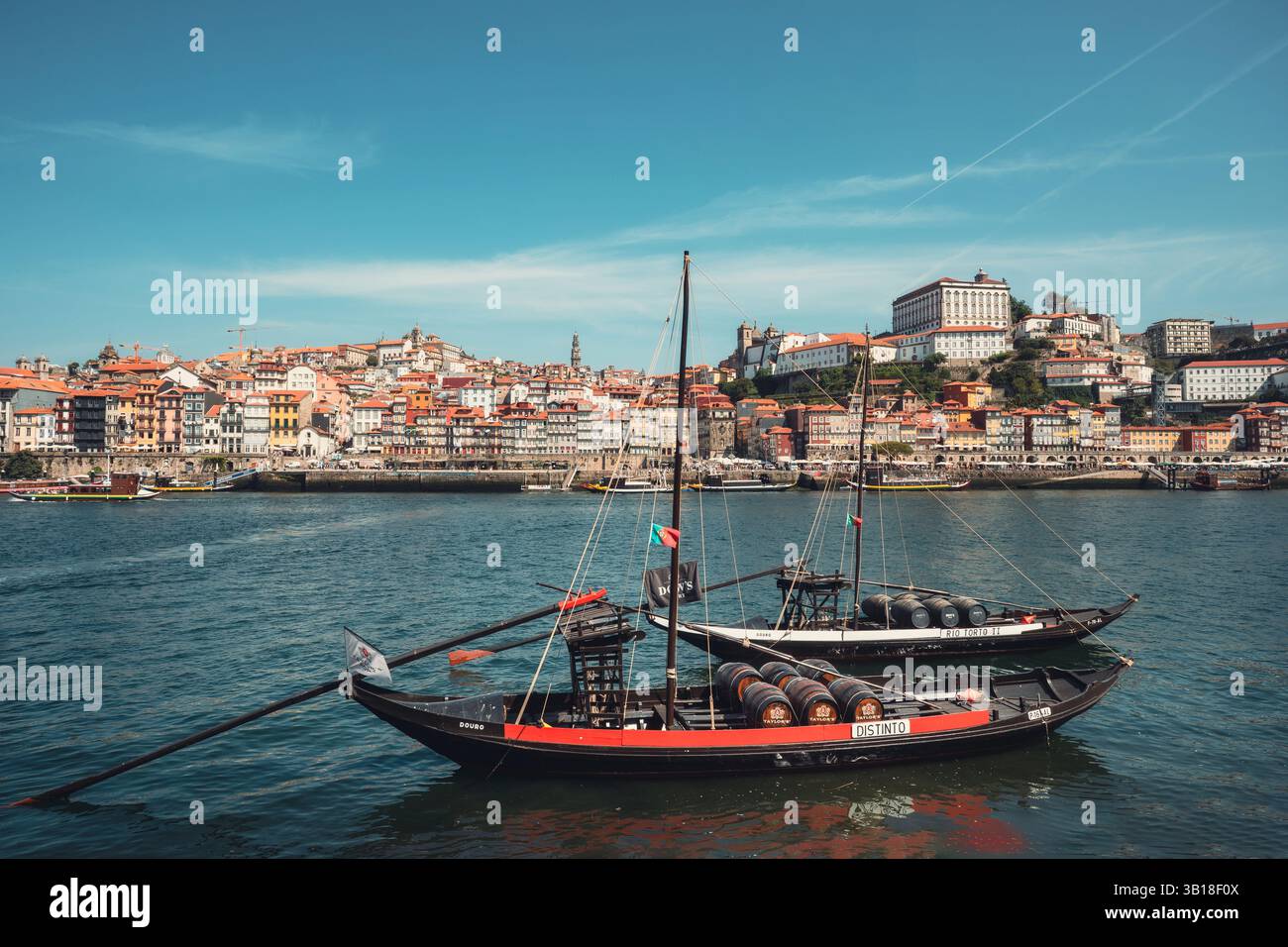Traditionelles Ragelo-Boot, das auf dem Fluss Douro mit farbenfrohen Gebäuden am Fluss Porto, Portugal, im Hintergrund verankert ist. Stockfoto