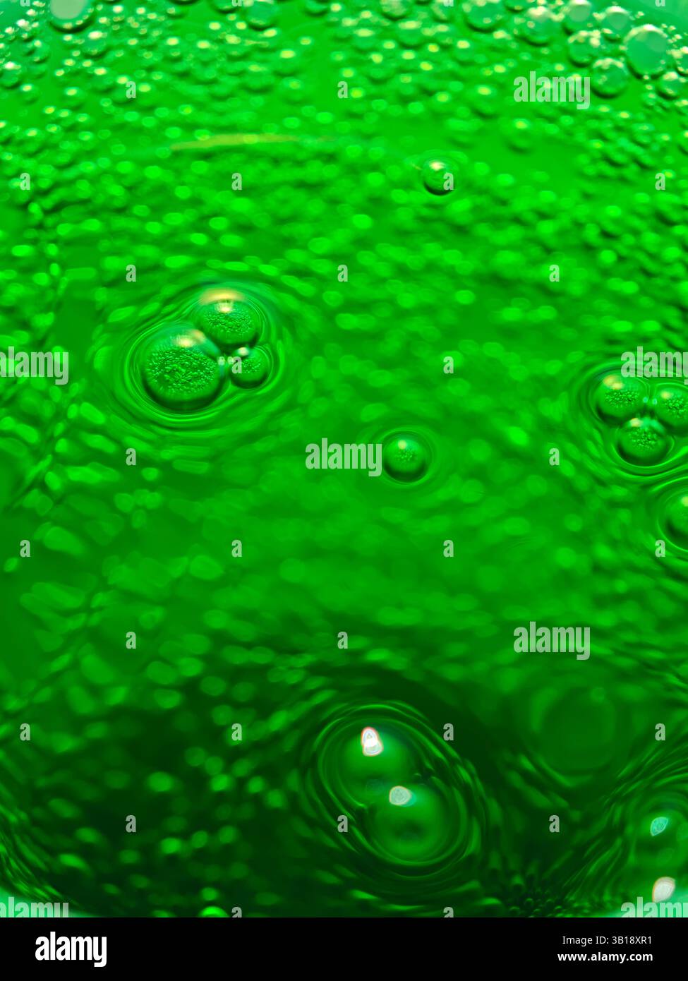 Erfrischendes grünes Soda mit Blasen, die konzentrische Kreise bilden, ideal für Hintergründe und Projekte im Zusammenhang mit alkoholfreien Getränken Stockfoto