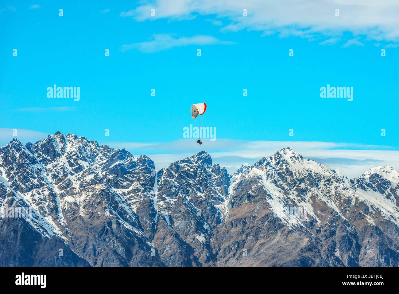 Gleitschirmfliegen über die schneebedeckten Remarkables Bergketten in Queenstown, Südinsel, Neuseeland Stockfoto